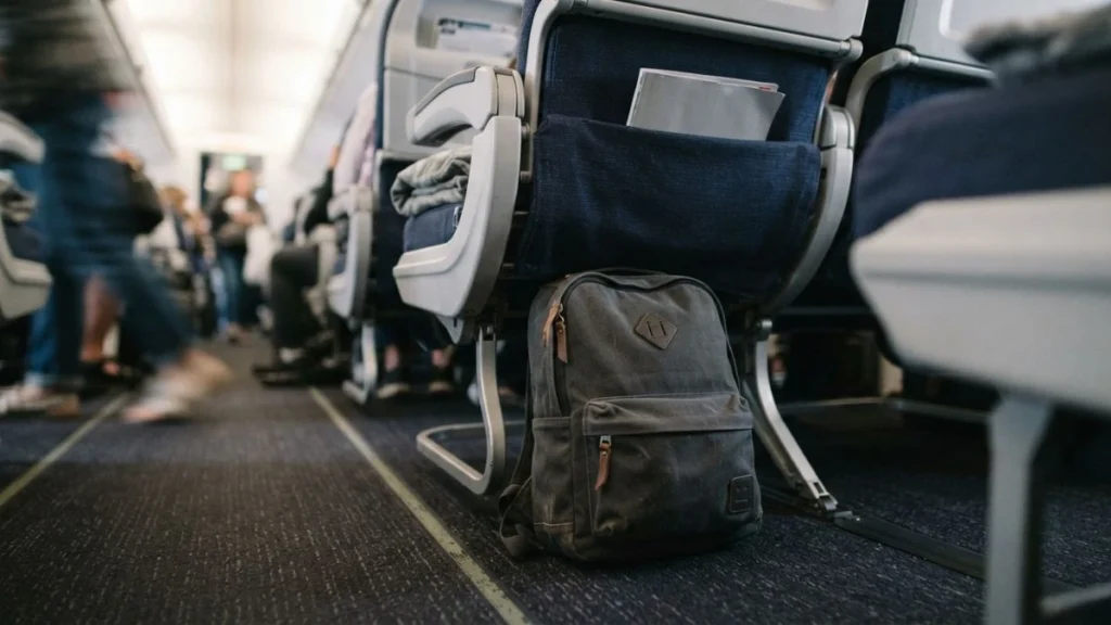 Backpack stowed under an airplane seat as a personal item